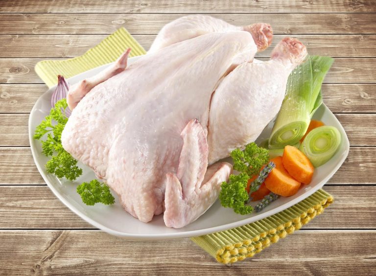 Rohes Hähnchen auf einem Teller mit Gemüse wie Karotten, Lauch und Salat.